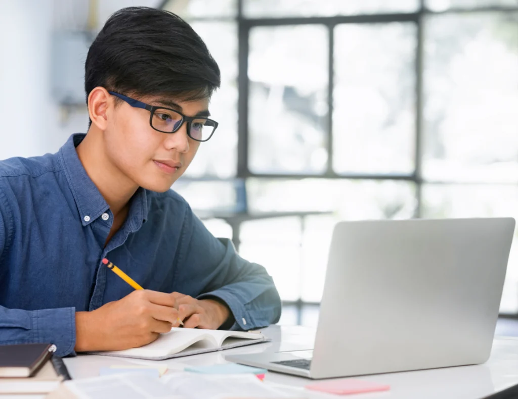 a male student with glasses using a laptop