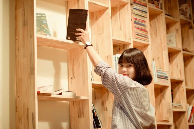 a girl returning a book from a the bookshelf