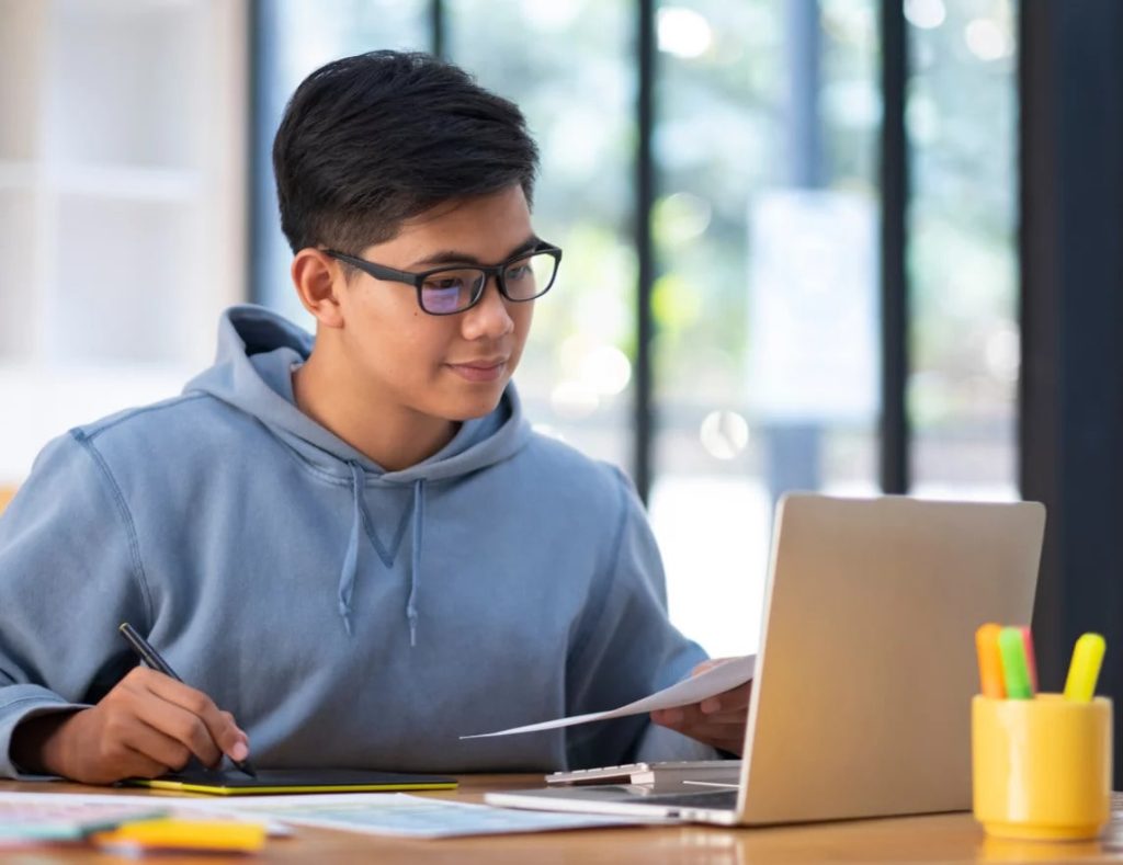 a male student studying in front of a laptop