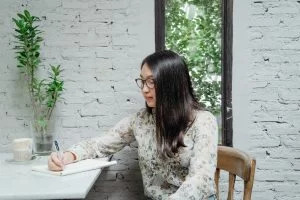 a girl writing in a notebook on a table