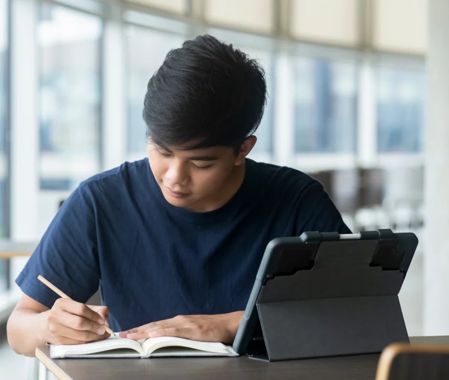 a male student writing on a notebook