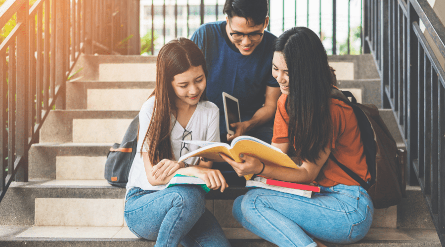 college students studying on a ladder holding a book